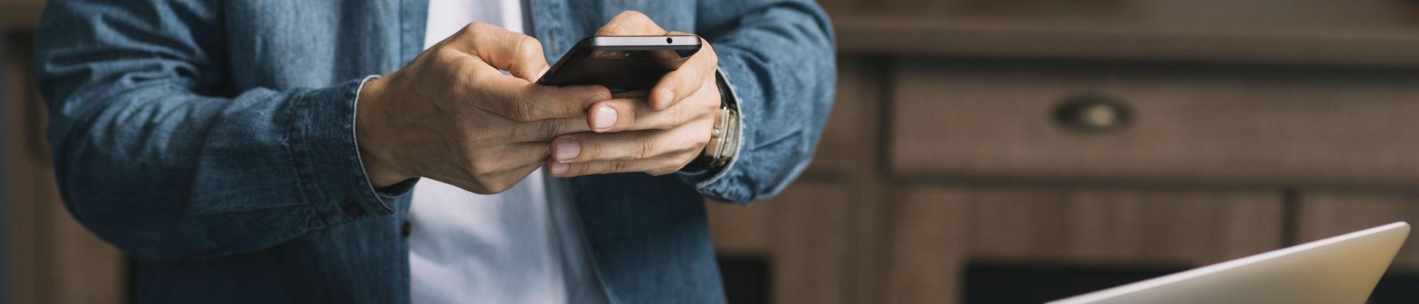 Un homme écrit un mail depuis son portable