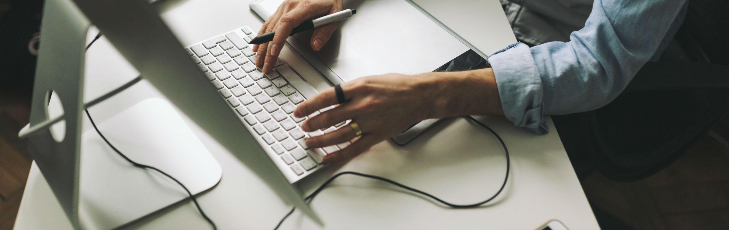 Un homme rédige un document sur son ordinateur